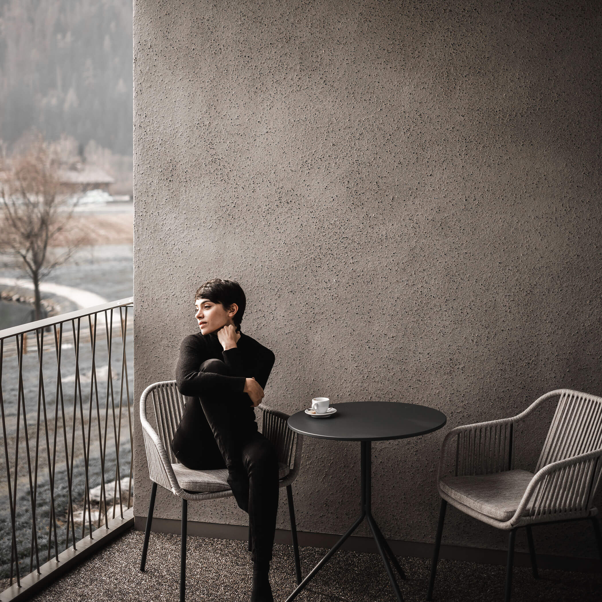 Donna seduta con un caffè su una sedia sul balcone e osserva la natura - OLM Nature Escape