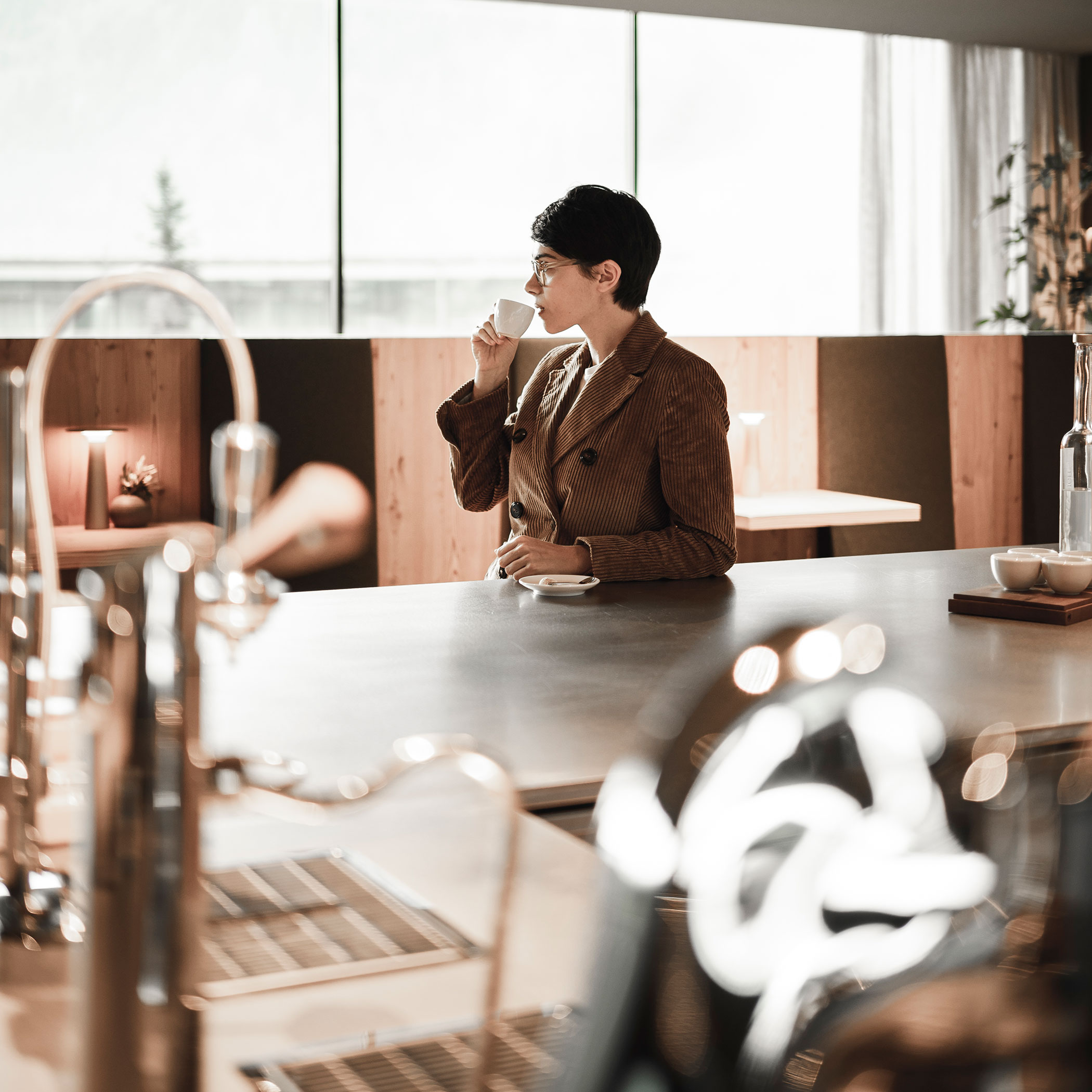 Una donna si appoggia al bar e beve un caffè - OLM Nature Escape