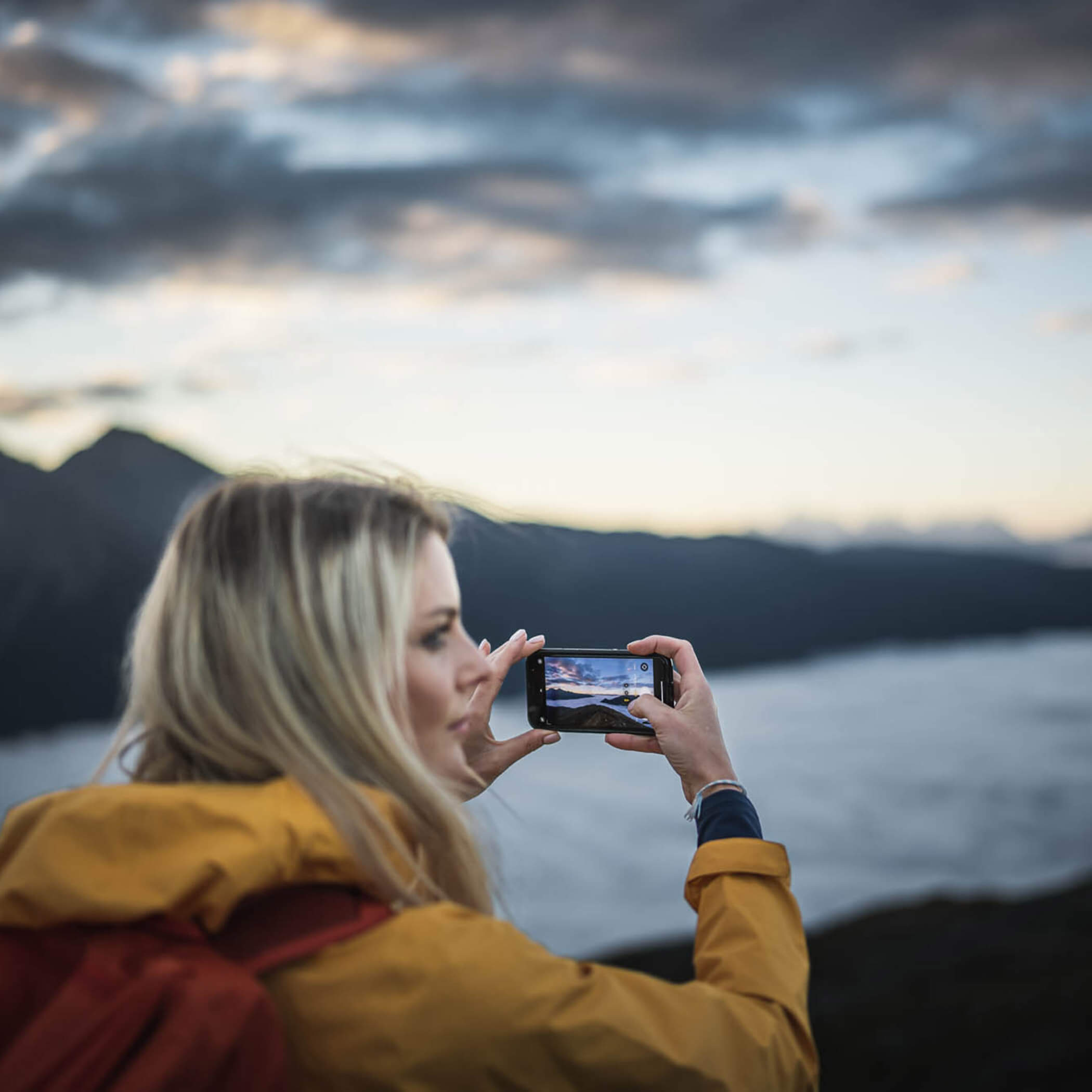 Donna che fotografa il tramonto sulle montagne dell'Alto Adige - OLM Nature Escape